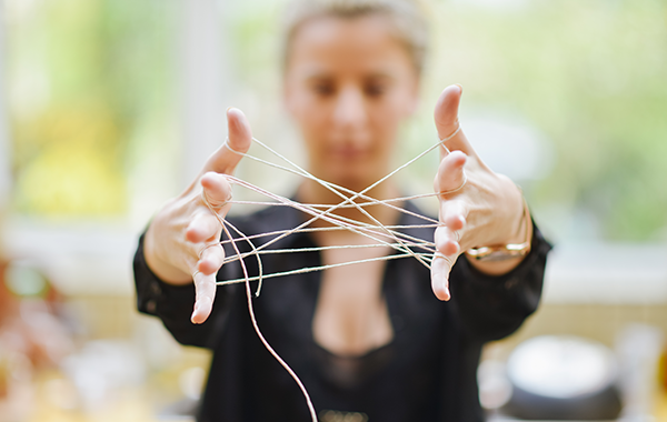 womans hands connected with tangled string